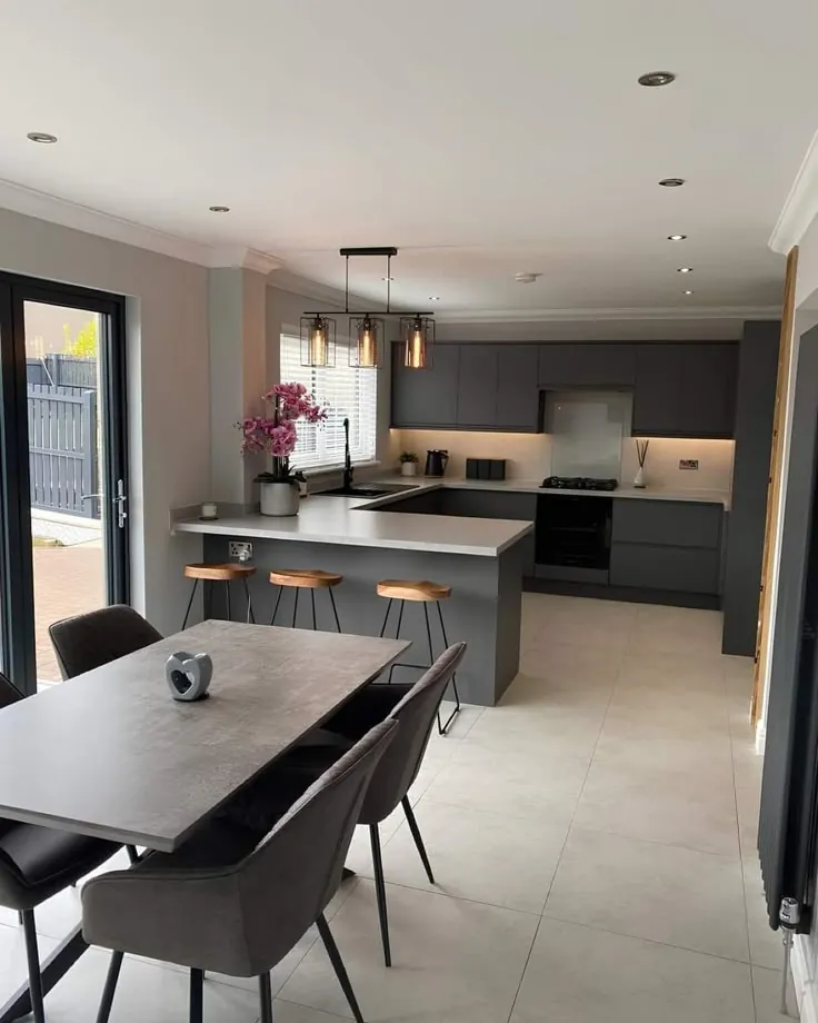 Cocina en gris grafito integrada con el comedor, con isla, luz bajo alacena y piso porcelanato